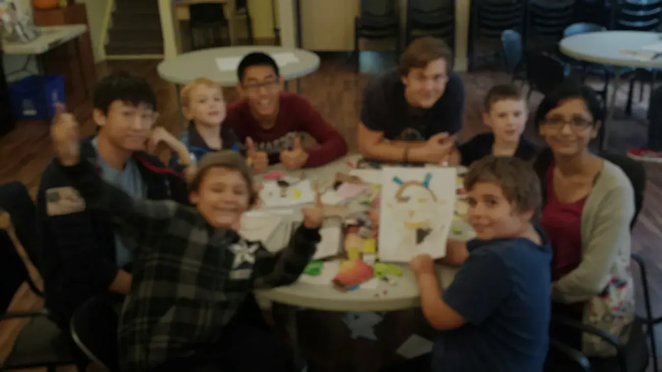 Blurred image of students around a table with children
